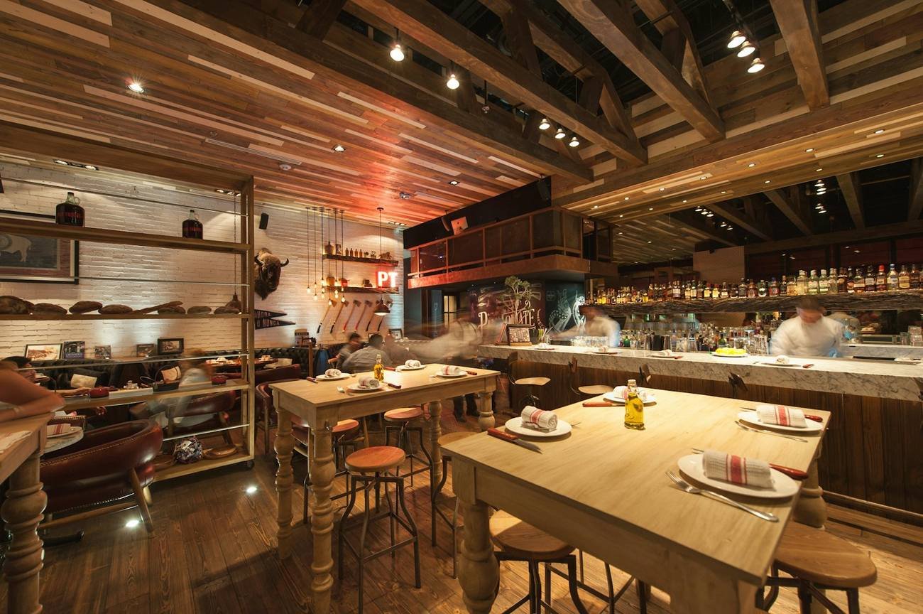 Dining room with wooden tables, greenery and hanging lights