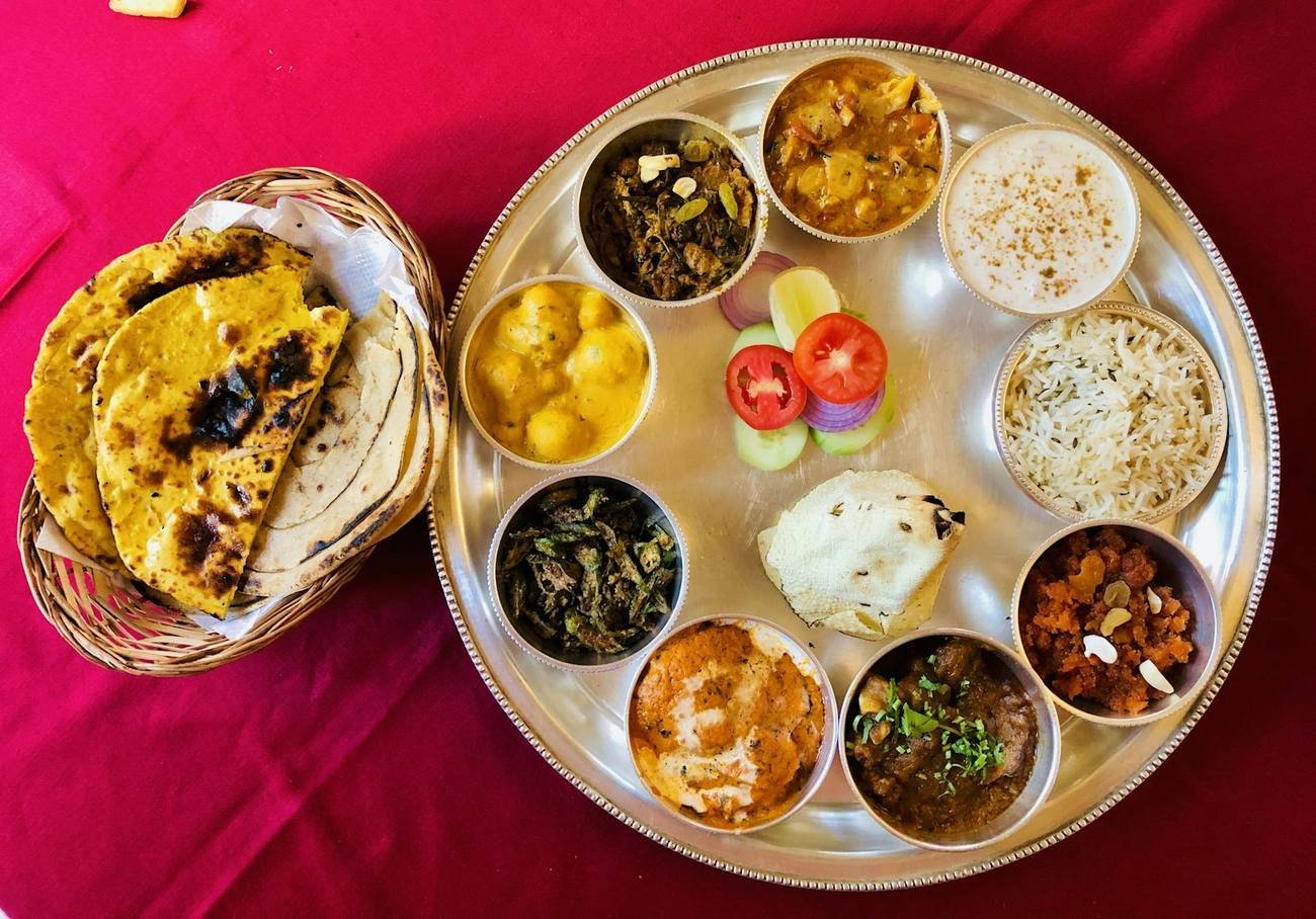 A large sharing platter of curries and rice with a basket of hot naan