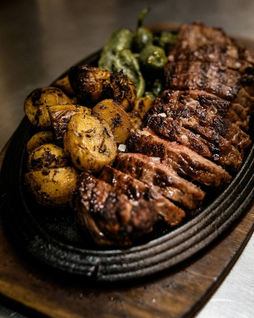 Grilled beef steak served with roast potatoes and greens
