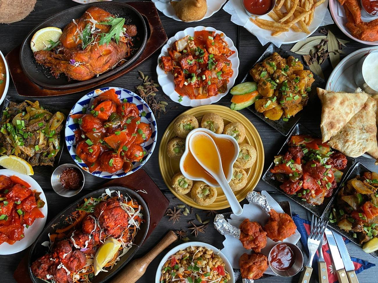 Overhead spread of curries, breads and small dishes on a metal platter